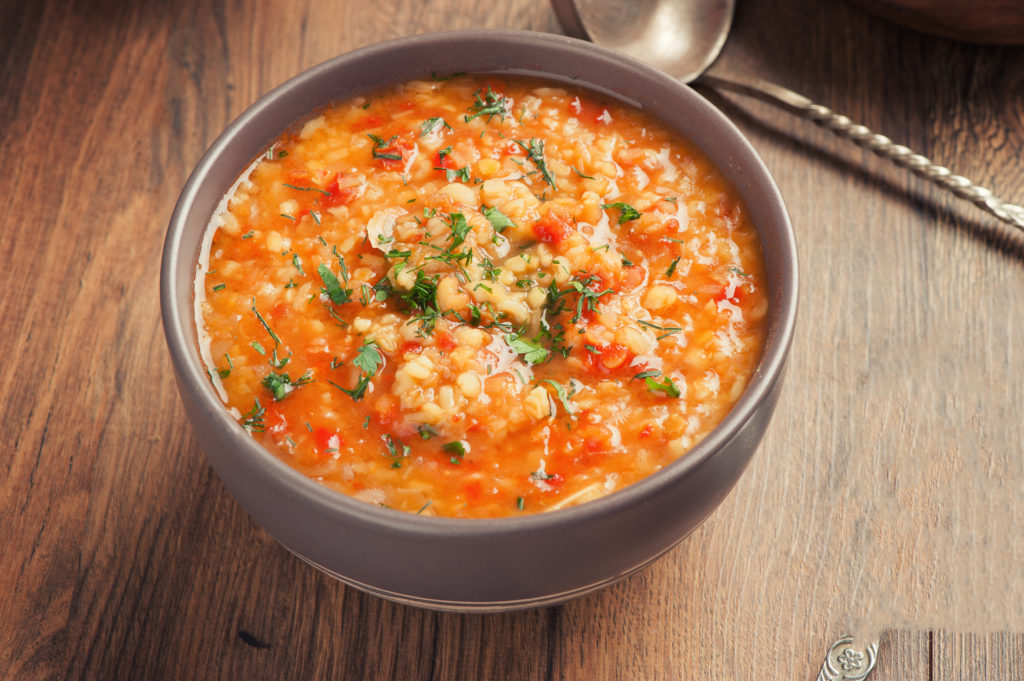 lentil soup made with tomatoes in bowl on dark wood table